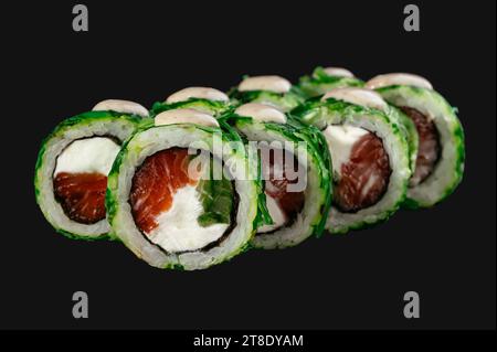 sushi roll con insalata chuka e salmone isolato su sfondo nero. Foto Stock