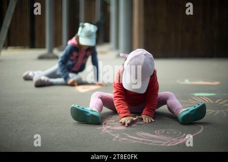 I bambini attingono all'asfalto. Disegnare in pastelli. Foto Stock