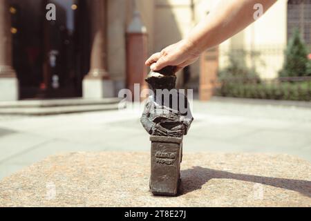 Donna che tocca una piccola statua nana sulla piazza del mercato di Breslavia. Famose piccole statue Foto Stock