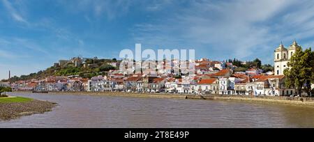 Vista sul lungomare di Alcacer do Sal dall'altra parte del fiume Sado con la chiesa di Santiago sulla destra e il castello sulla sinistra Foto Stock