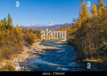 Splendido paesaggio autunnale, fiume di montagna, alberi gialliti, montagne con cime innevate. Incantevole paesaggio montano in autunno Foto Stock
