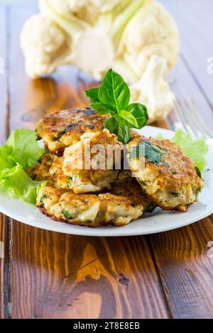 cotolette di cavolfiore fritte vegetariane, in un piatto su un tavolo di legno. Foto Stock