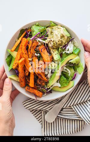 Spicchi di patate dolci al forno con salsa di avocado e hummus, vista dall'alto. Insalata pranzo vegana sana. Foto Stock