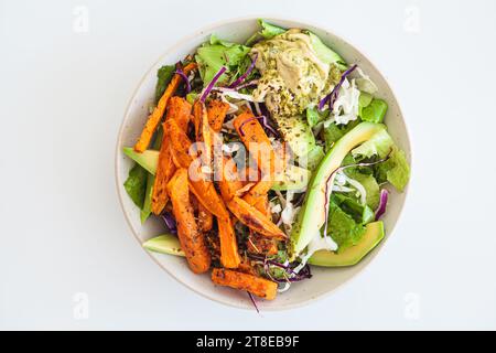 Spicchi di patate dolci al forno con salsa di avocado e hummus, vista dall'alto. Insalata pranzo vegana sana. Foto Stock