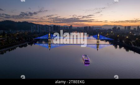 Pechino, Cina. 20 novembre 2023. Questa foto aerea scattata il 20 novembre 2023 mostra un ponte illuminato per celebrare la giornata Mondiale dei bambini sul fiume Xin'an nella città di Huangshan, nella provincia di Anhui della Cina orientale. Crediti: Fan Chengzhu/Xinhua/Alamy Live News Credit: Xinhua/Alamy Live News Foto Stock