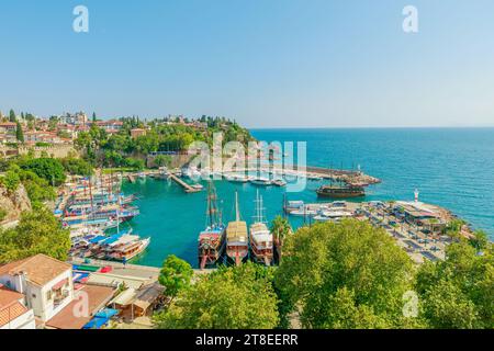 Vista panoramica di Antalya, Turchia. Le profonde acque blu-verdi del Mar Mediterraneo incontrano un vivace porto pieno di barche di varie dimensioni. Un bianco Foto Stock