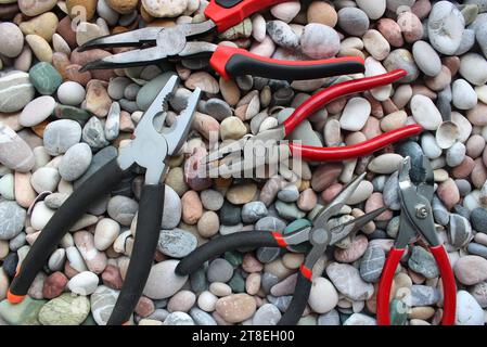 Foto concettuale con set di diversi tipi di pinze meccaniche sulla vista dall'alto Smooth Rocks Foto Stock