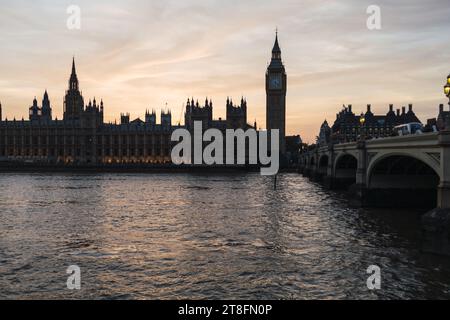 Sagoma delle Case del Parlamento e del Big Ben contro un vivace cielo al tramonto, con riflessi sul Tamigi. Foto Stock