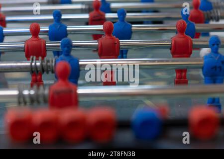 Una vista ravvicinata di un gioco da tavolo a foosball con personaggi in miniatura rossi e blu posizionati su barre di metallo, pronti per il gioco. Foto Stock