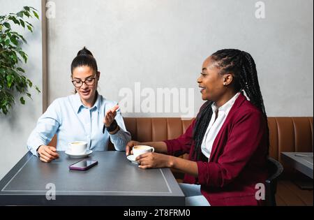 Due giovani colleghi d'affari che fanno una pausa nella vicina caffetteria bevono un caffè parlando di vita privata, per conoscersi meglio. STAF Foto Stock