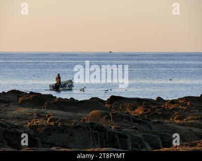 Pescatore isolato che naviga su un peschereccio alla luce del mattino presto, Bretagna, Francia Foto Stock