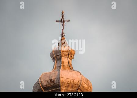 Bella croce illuminata in cima alla chiesa contro il cielo limpido Foto Stock