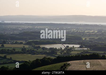 I campi di pannelli solari si trovano accanto all'autostrada M5 a Michael Wood nella campagna del Gloucestershire, con l'estuario del Severn e la Foresta di Dean Foto Stock