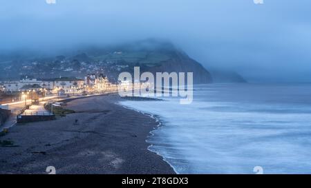 L'Esplanade fronte mare e' illuminata di notte nella cittadina balneare di Sidmouth, sulla Jurassic Coast del Devon. Foto Stock