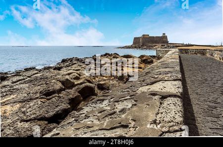 Una vista lungo la strada rialzata verso l'isolotto degli inglesi ad Arrecife, Lanzarote, in un pomeriggio di sole Foto Stock