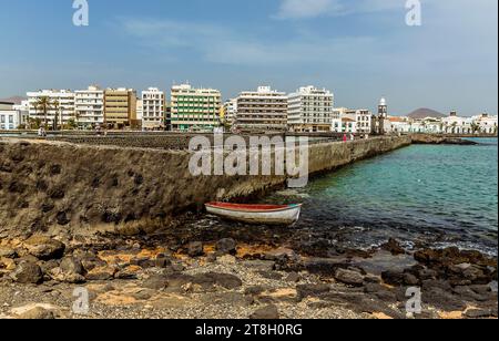 Una vista lungo il lato della strada rialzata fino alla costa di Arrecife, Lanzarote in un pomeriggio di sole Foto Stock