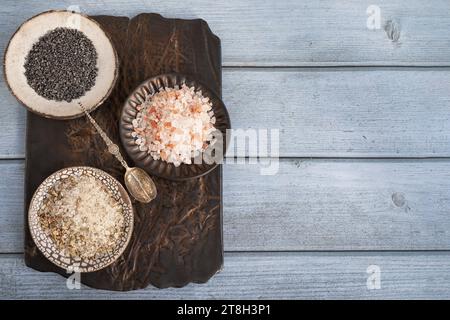 diversi tipi di sale. Tre diversi tipi di sale in piatti artigianali fatti a mano su una tavola di argilla. Sale marino alle erbe bianche, rosa himalayano e nero Foto Stock