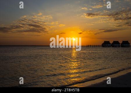 Foto orizzontale del tramonto che si riflette nel mare con molo e capanne a Zanzibar, Tanzania Foto Stock