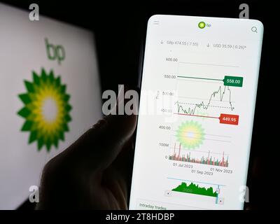 Persona che possiede uno smartphone con una pagina Web della compagnia petrolifera britannica BP plc davanti al logo aziendale. Concentrarsi sul centro del display del telefono. Foto Stock