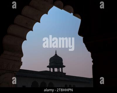 Una piccola cupola in stile architettonico moghul può essere osservata nel tardo pomeriggio attraverso un arco presso il forte Rosso di Agra in Uttar Pradesh, India. Foto Stock