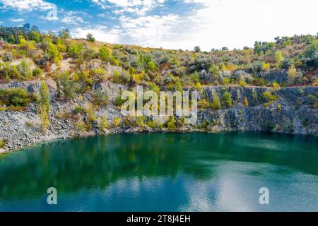 Cava di granito inondata e abbandonata con acqua turchese cristallina. Soleggiata giornata autunnale. Drone. Vista aerea Foto Stock