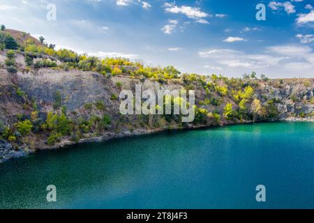 Cava di granito inondata e abbandonata con acqua turchese cristallina. Soleggiata giornata autunnale. Drone. Vista aerea Foto Stock