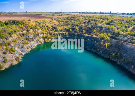 Cava di granito inondata e abbandonata con acqua turchese cristallina. Soleggiata giornata autunnale. Drone. Vista aerea Foto Stock