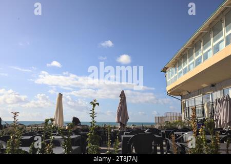 Genova, Italia - novembre 2023 - tavoli e sedie di un ristorante su una passeggiata accanto al frangiflutti in riva al mare Foto Stock