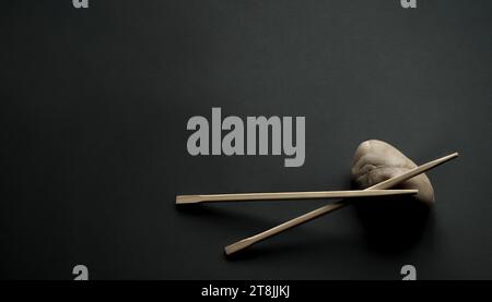 Bacchette di bambù giapponesi e pietra chiara su sfondo grigio scuro. Minimalismo, composizione in un angolo, ampio spazio di copia Foto Stock