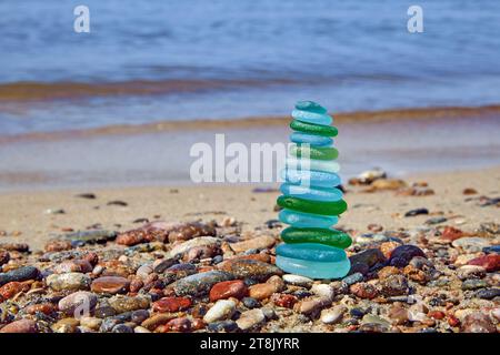 Piramide bilanciata di frammenti di bottiglia lucidati al mare sulla riva del mare Foto Stock
