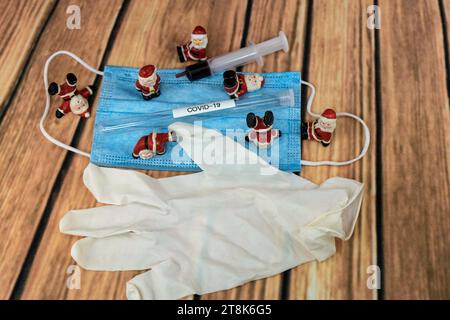 Santa Klauses con maschera chirurgica e provetta, immunizzazione, Natale con Corona Foto Stock