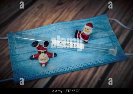 Santa Klauses con maschera chirurgica e provetta, Natale con Corona Foto Stock