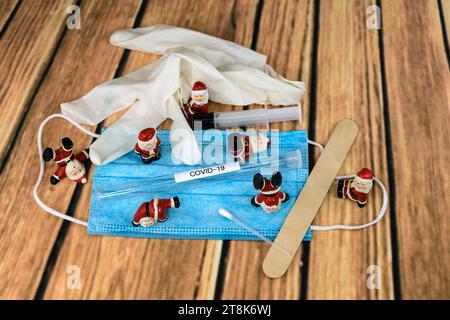 Santa Klauses con maschera chirurgica e provetta, immunizzazione, Natale con Corona Foto Stock