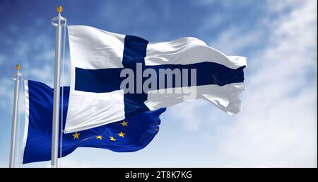 Bandiere nazionali della Finlandia che sventolano al vento con la bandiera dell'Unione europea in una giornata limpida. rendering dell'illustrazione 3d. Tessuto ondulato Foto Stock