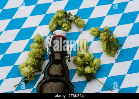 Luppolo comune (Humulus lupulus), birra in bottiglia e coni di luppolo con bandiera bavarese, Germania, Baviera Foto Stock