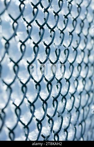 Neve sulla recinzione delle maglie della catena contro il cielo blu Foto Stock
