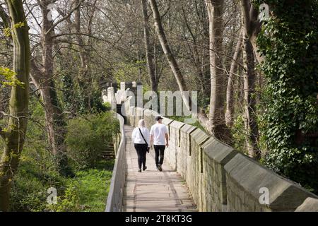 YORK, Regno Unito - 17 aprile 2023. Una coppia di turisti cammina lungo le mura della città di York, le mura cittadine più lunghe dell'Inghilterra. York, Regno Unito Foto Stock