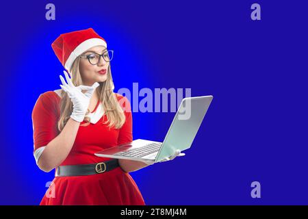 Bionda e il giovane Babbo Natale fanno un gesto ok con la mano sullo schermo di un notebook Foto Stock