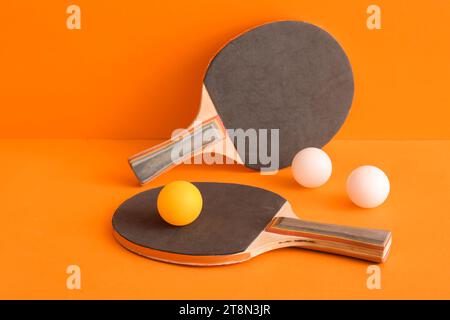 Racchette da ping pong e palline su sfondo arancione Foto Stock