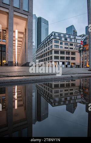 Riflesso in una pozzanghera tra grattacieli. Paesaggio urbano con edifici e strade moderni. Compagnie assicurative e banche come paesaggio urbano Foto Stock