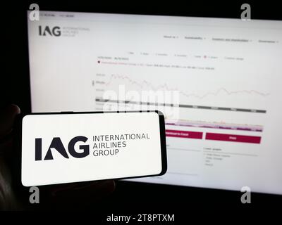 Persona che possiede un telefono cellulare con il logo di International Consolidated Airlines Group SA (IAG) davanti alla pagina Web. Concentrarsi sul display del telefono. Foto Stock