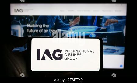 Persona che possiede uno smartphone con il logo di International Consolidated Airlines Group SA (IAG) davanti al sito Web. Concentrarsi sul display del telefono. Foto Stock