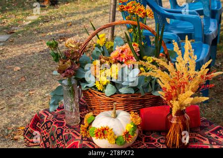 Un primo piano di un cesto intrecciato e di una zucca piena di fiori all'aperto Foto Stock