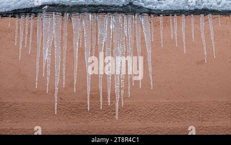 Ghiaccioli sul tetto. Lo scarico è pieno di neve e ghiaccio. Ghiaccio cadere concetto di pericolo. Foto Stock