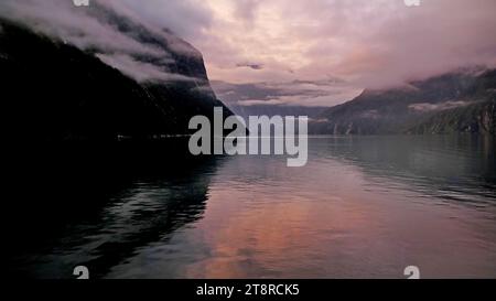 Dawn. Milford Sound NZ, Milford Sound (Māori: Piopiotahi) è un fiordo nel sud-ovest dell'Isola del Sud della nuova Zelanda, all'interno del Parco Nazionale di Fiordland, della riserva marina di Piopiotahi (Milford Sound) e del te Wahipounamu, sito patrimonio dell'umanità. È stata giudicata la migliore destinazione di viaggio al mondo in un sondaggio internazionale (i Travelers' Choice Destinations Awards 2008 di TripAdvisor) ed è stata acclamata come la destinazione turistica più famosa della nuova Zelanda. Rudyard Kipling l'aveva precedentemente chiamata l'ottava meraviglia del mondo Foto Stock