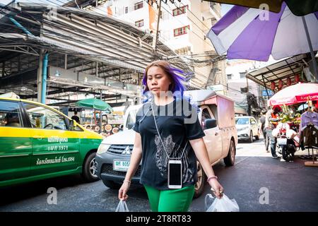 Una giovane signora tailandese si fa strada attraverso il mercato di Pratunam per fare shopping. Foto Stock