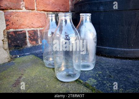 vecchie bottiglie di latte da pinta tradizionali del diario di cotteswold lasciate alle porte di una casa al mattino di ormskirk, lancashire, inghilterra, regno unito Foto Stock