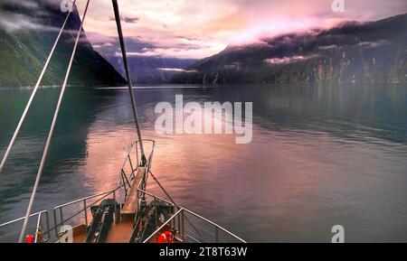 Crociera all'alba a Milford Sound/nuova Zelanda, Milford Sound è un fiordo nel sud-ovest della New Zealands South Island. È noto per il torreggiante Mitre Peak, oltre a foreste pluviali e cascate come Stirling e Bowen Falls, che precipitano lungo i suoi lati a picco. Il fiordo ospita colonie di foche da pelliccia, pinguini e delfini Foto Stock