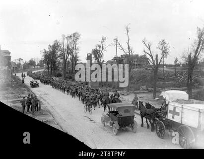 Un battaglione neozelandese che attraversava Bapaume, durante la prima guerra mondiale, Una vista dalla parte posteriore di un battaglione neozelandese che passava attraverso Bapaume riconquistata in Francia. Mostra un'ambulanza trainata da cavalli dietro una colonna di truppe per lo più a piedi che si muovono lungo una strada. Alcuni uomini sono montati e un altro è in bicicletta. Anche le auto a motore sono in viaggio. Sullo sfondo c'è lo zuccherificio gravemente danneggiato, 14 settembre 1918 Foto Stock