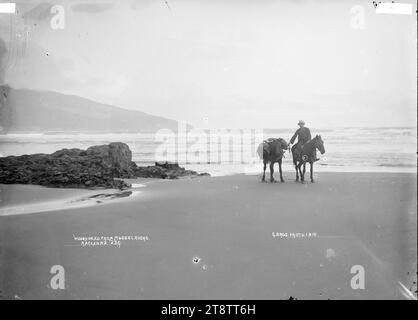 Mussel Rocks (te Kaha Point), vicino a Raglan, nuova Zelanda, sulla spiaggia di Mussel Rocks (nelle vicinanze di Raglan, nuova Zelanda) 1 agosto 1910, fotografata dai fratelli Gilmour. Woody Head è in lontananza. L'uomo a cavallo e con un cavallo da corsa non è identificato Foto Stock
